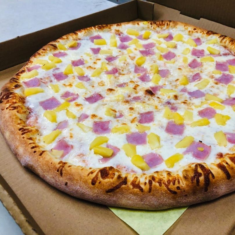 A Marco Polo Pizza Hawaiian pizza with ham and pineapple in a cardboard box.