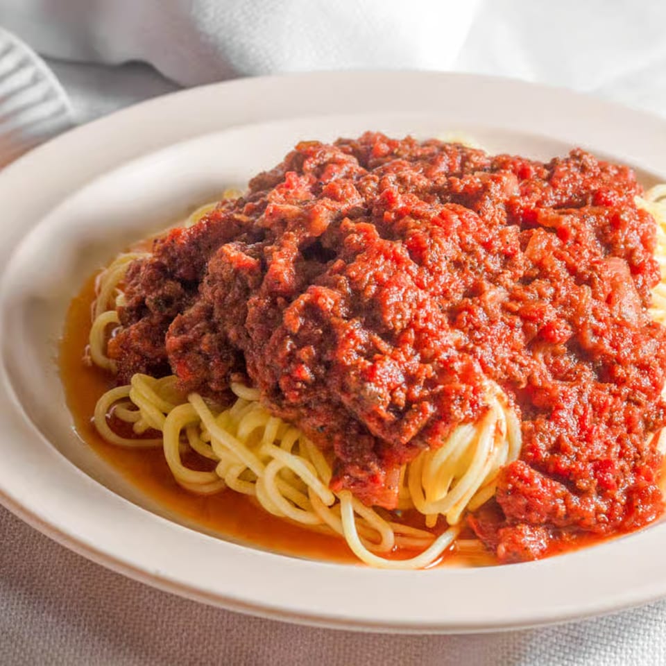 A plate of spaghetti with a rich, chunky red marinara sauce, ready to be served.