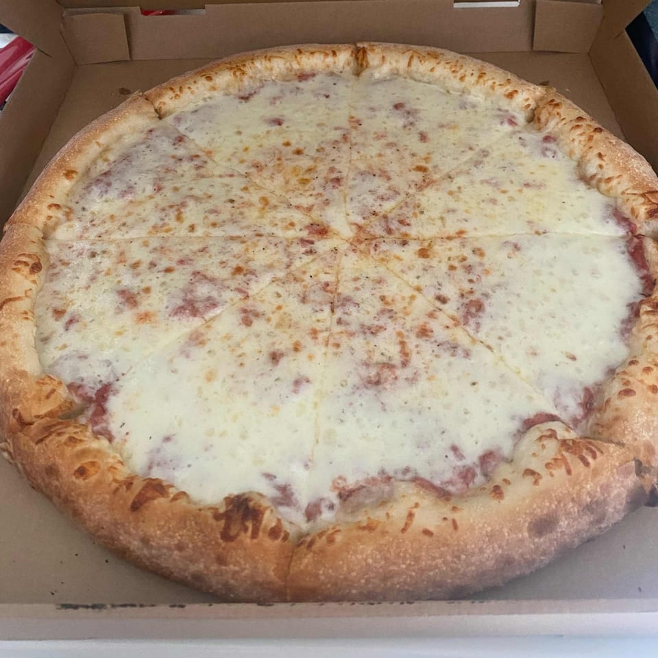 A whole Marco Polo Pizza, cut into slices, with a thick crust and melted white cheese.